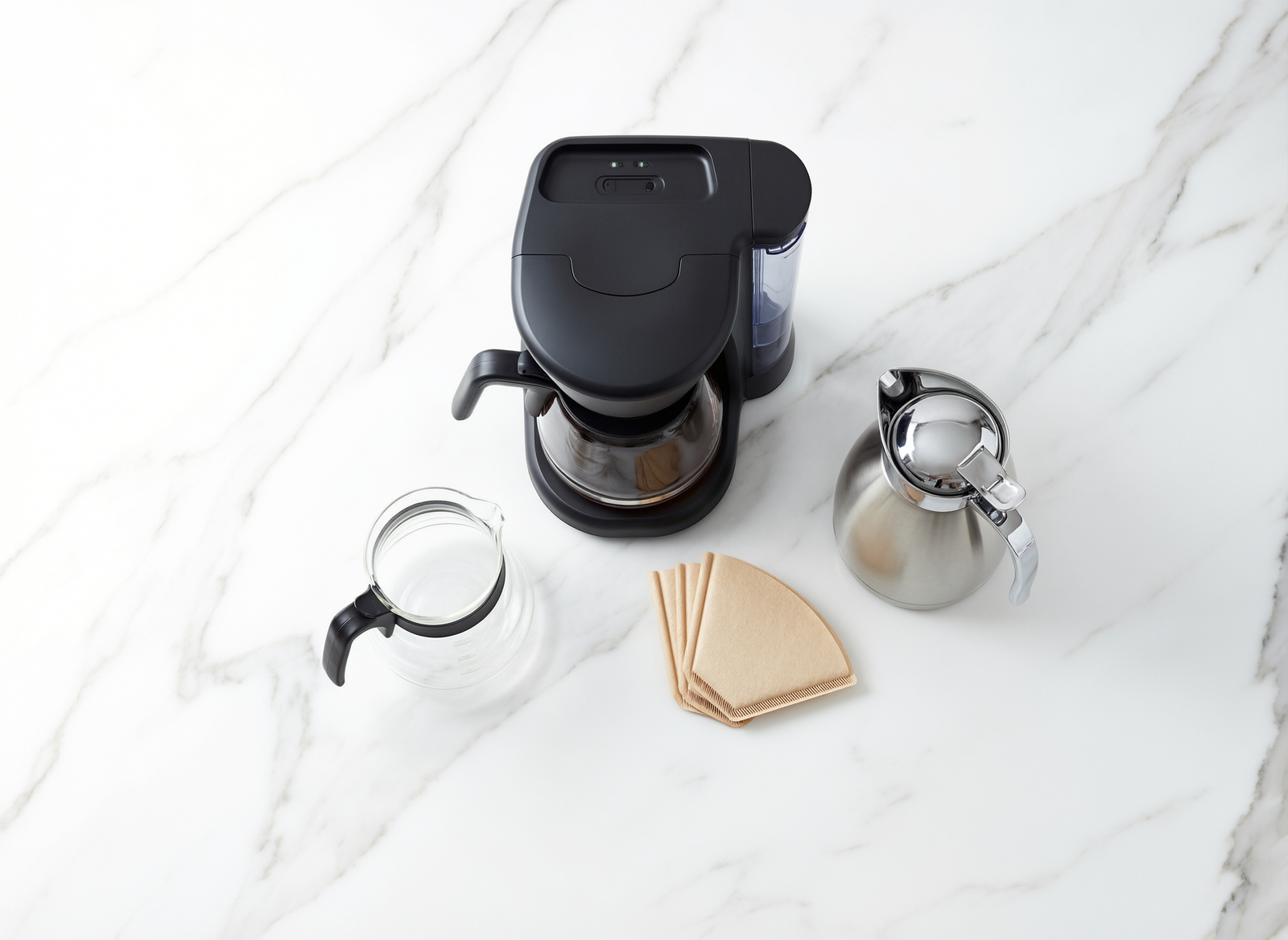 Flat lay of drip coffee makers with glass and thermal carafes, paper filters and freshly ground coffee beans